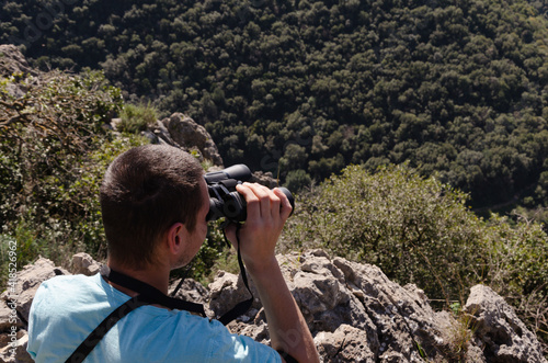 a young guy looks at the landscape with binoculars