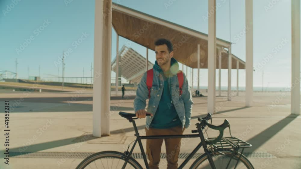 Portrait of handsome millennial generation z young man in cool hipster clothes outfit stand with his commuter city bike in direct sunlight, look into camera, smile confident and happy Portrait of handsome millennial generation z young man in cool hipster clothes outfit stand with his commuter city bike in direct sunlight, look into camera, smile confident and happy