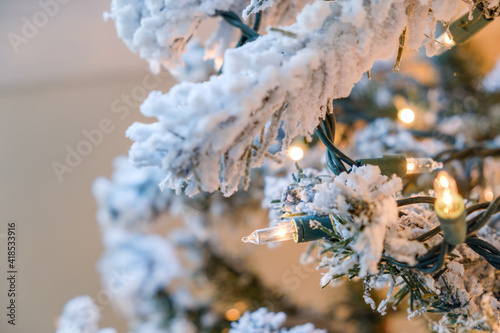 White Christmas Holiday lights on a artificial snow flocked Christmas tree in an American Home