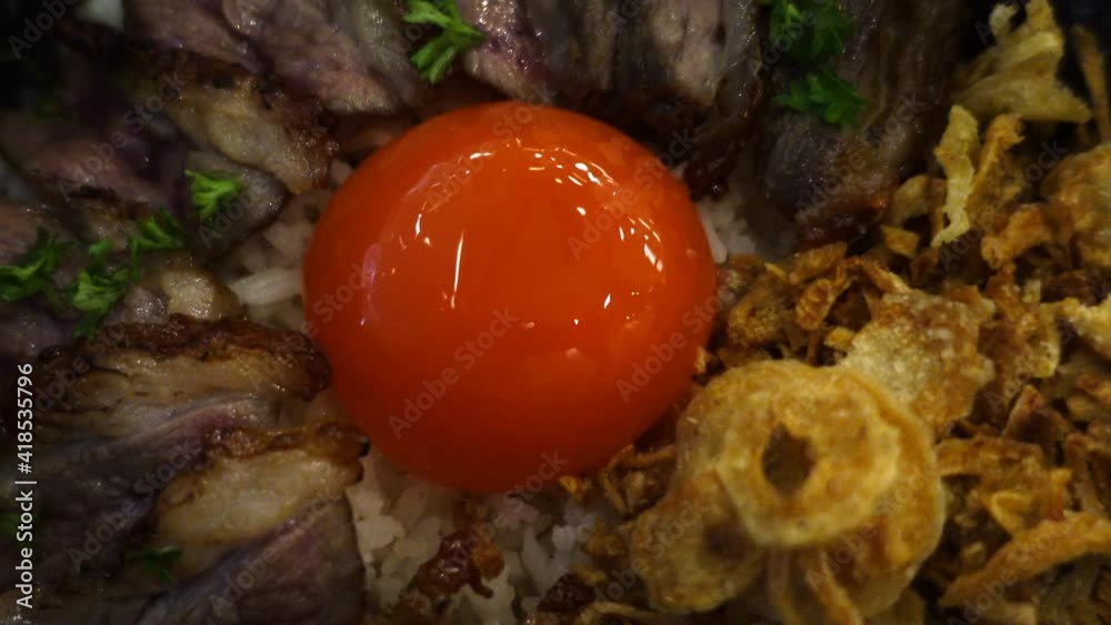 Soy sauce cured pickled egg yolk over steak beef rice and garlic Asian