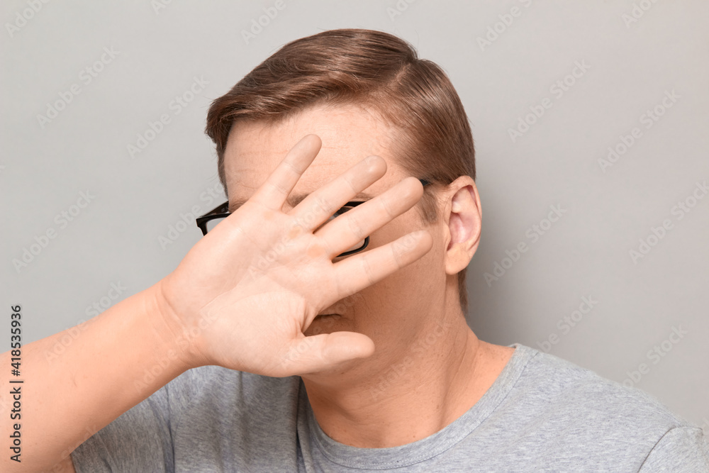 Shot of mature man raising hand and covering his face Shot of mature man raising hand and covering his face