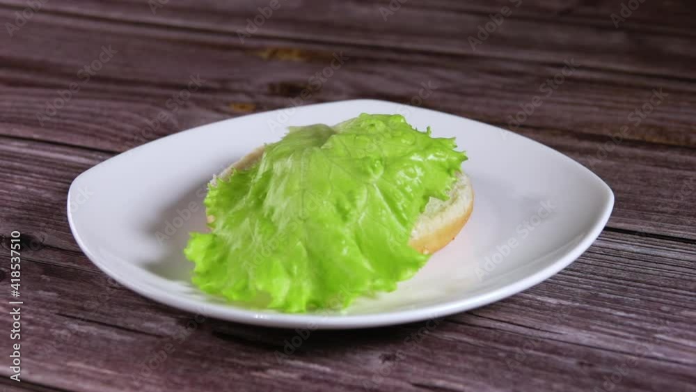 Fresh Lettuce Falls on Burger Bun. Slow Motion Fresh Lettuce Falls on Burger Bun. Slow Motion