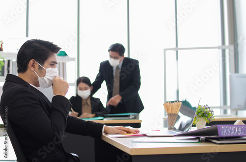Business workers wear masks to protect and take care of their health.young asia business man feeeling sick in work office