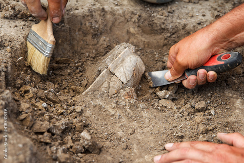 Archaeological excavations, archaeologists work, dig up an ancient clay artifact with special tools
