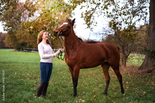 Eine hübsche langhaarige, lockige, blonde Frau kuschelt mit ihrem Pferd