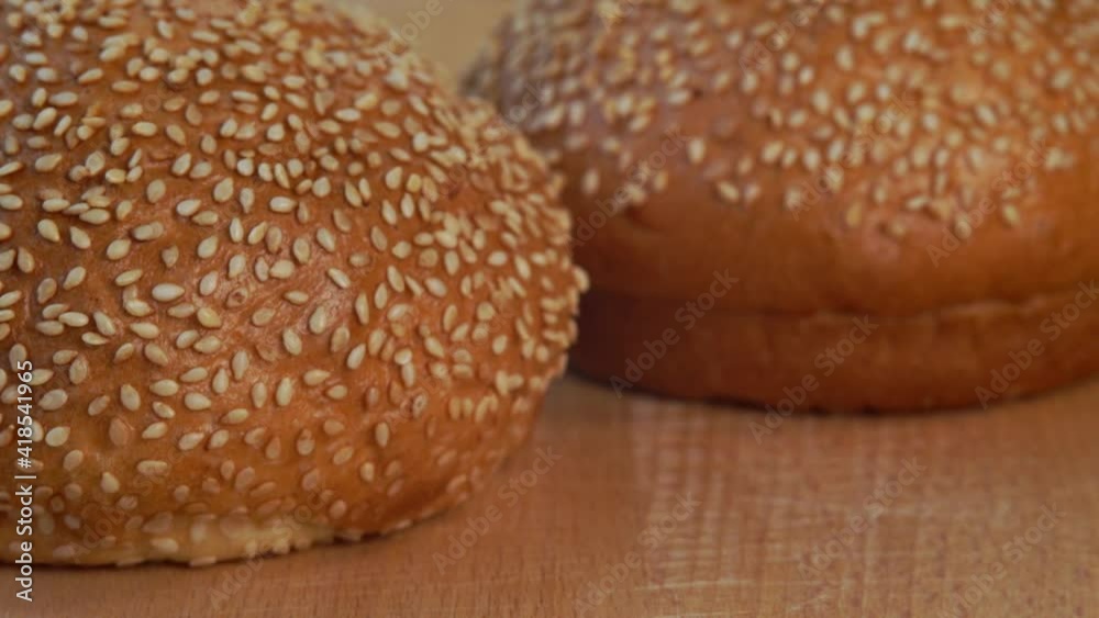 Camera movement on fresh hot sandwich bun with sesame seeds on wooden cutting board. Food bread breakfast concept Camera movement on fresh hot sandwich bun with sesame seeds on wooden cutting board. Food bread breakfast concept