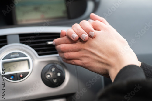 The girl squeezes her hands and warms them over the hot air outlet in the car. Cold hands. © fotodrobik