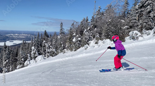 Girl skier at Mont Tremblant slopes, with lake on the background, Quebec, Canada
