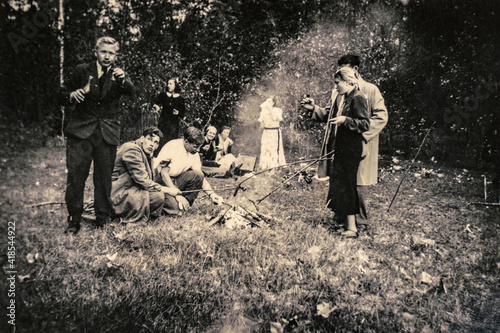 Germany - CIRCA 1930s: Adult friends relaxing at forest during picnic. Vintage Art deco era photo photo