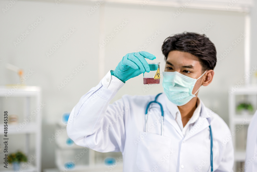 A scientist holding a beaker and looking at chemicals In it Inside the laboratory A scientist holding a beaker and looking at chemicals In it Inside the laboratory