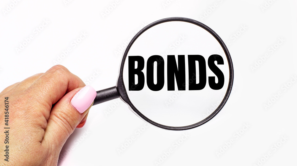 Woman's hand holds a magnifying glass with the inscription BONDS Woman's hand holds a magnifying glass with the inscription BONDS