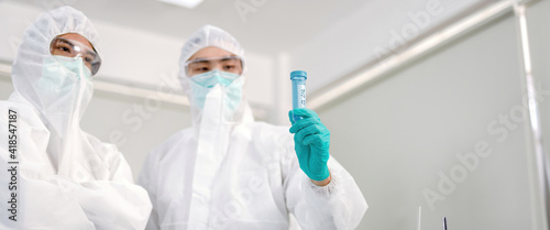 A man in a ppe suit holding a virus science.