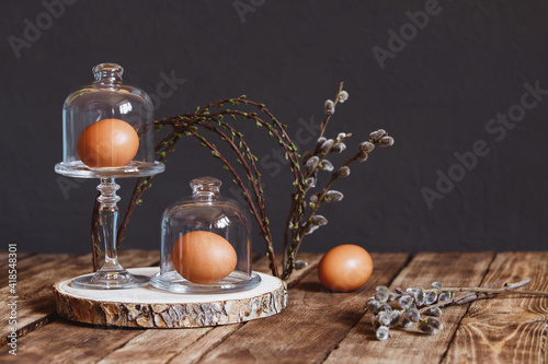 Easter spring composition with three chicken egg in a glass cloche, spring willow branches in the form of an arch. The concept of rustic decoration and Easter table setting, a protein diet.