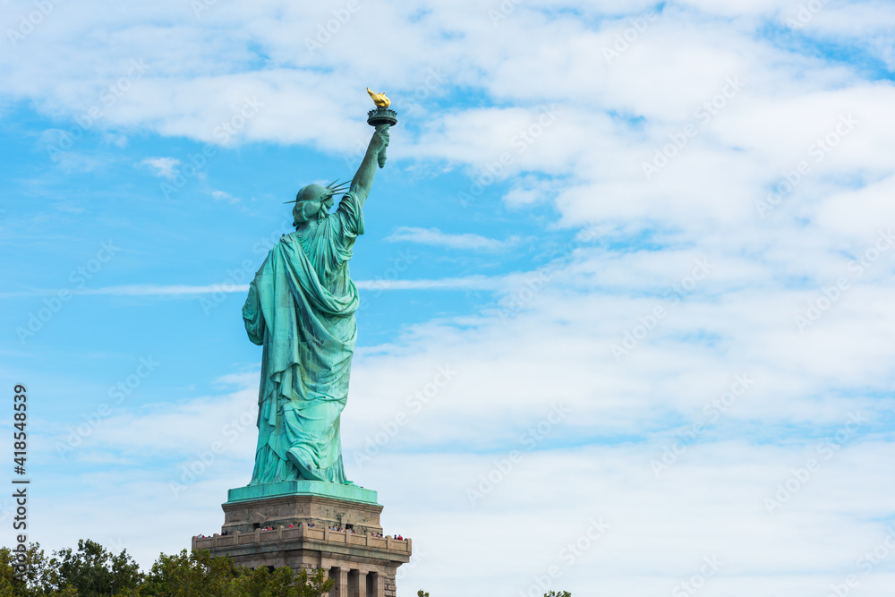Fototapeta premium Statue of Liberty National Monument back view with blue sky background. New York, USA.