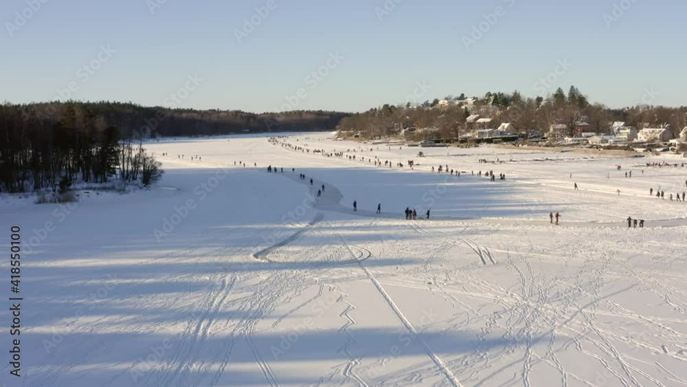 Many people ice skating in the nature on frozen water lake or pond. Ring or rink without snow skaters circling around. Winter activity in the nature. Fun sport for families in aerial drone shot Many people ice skating in the nature on frozen water lake or pond. Ring or rink without snow skaters circling around. Winter activity in the nature. Fun sport for families in aerial drone shot