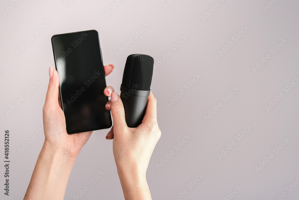 Concept for Clubhouse Drop-in audio is a voice-activated social media app. Smartphone and microphone in female hands on a light background. Concept for Clubhouse Drop-in audio is a voice-activated social media app. Smartphone and microphone in female hands on a light background.