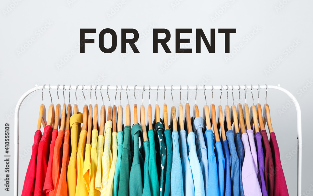 Rack with bright clothes for rent on light background Rack with bright clothes for rent on light background