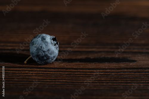 Blueberry in drops of water on wooden table. Copy space, close up