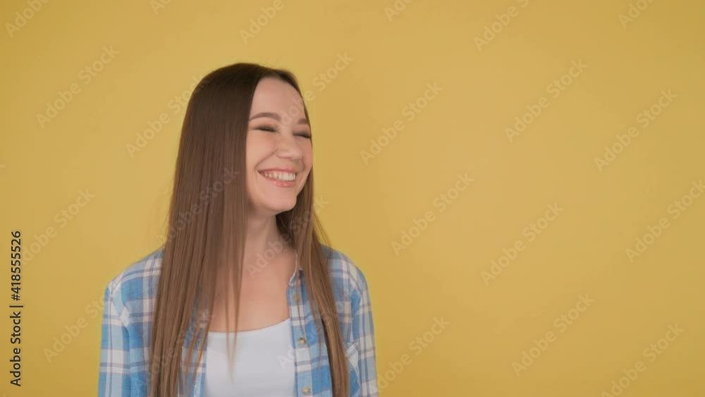 Portrait of a young long-haired laughing student woman on yellow background 4K Portrait of a young long-haired laughing student woman on yellow background 4K