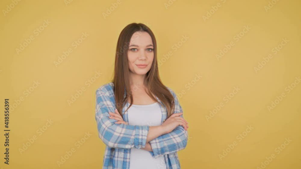 Portrait of a young student woman on yellow background isolated. Woman folded hands on the chest. Portrait of a young student woman on yellow background isolated. Woman folded hands on the chest.