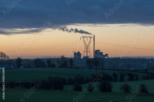 Early morning landscape with factory in the distance with sunrise sky at the background.