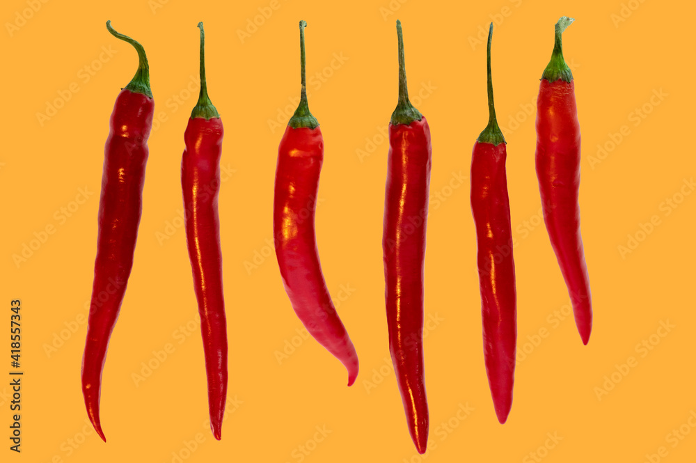 Mehrere Chili in einer Reihe auf orangem Hintergrund Mehrere Chili in einer Reihe auf orangem Hintergrund