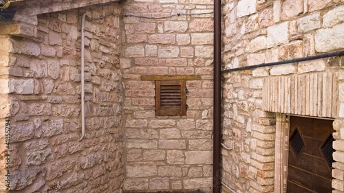 Isolated tiny window with wooden shutters in a medieval brick building (Marche, Italy, Europe)