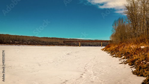 Views of concrete and steel bridge crossing a frozen North Saskatchewan River, Hensberg Alberta Canada.  Hiking the Iron Horse trail in the winter