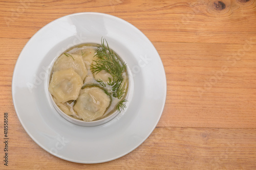 Homemade meat dumplings with broth and sour cream. View from above, copy space