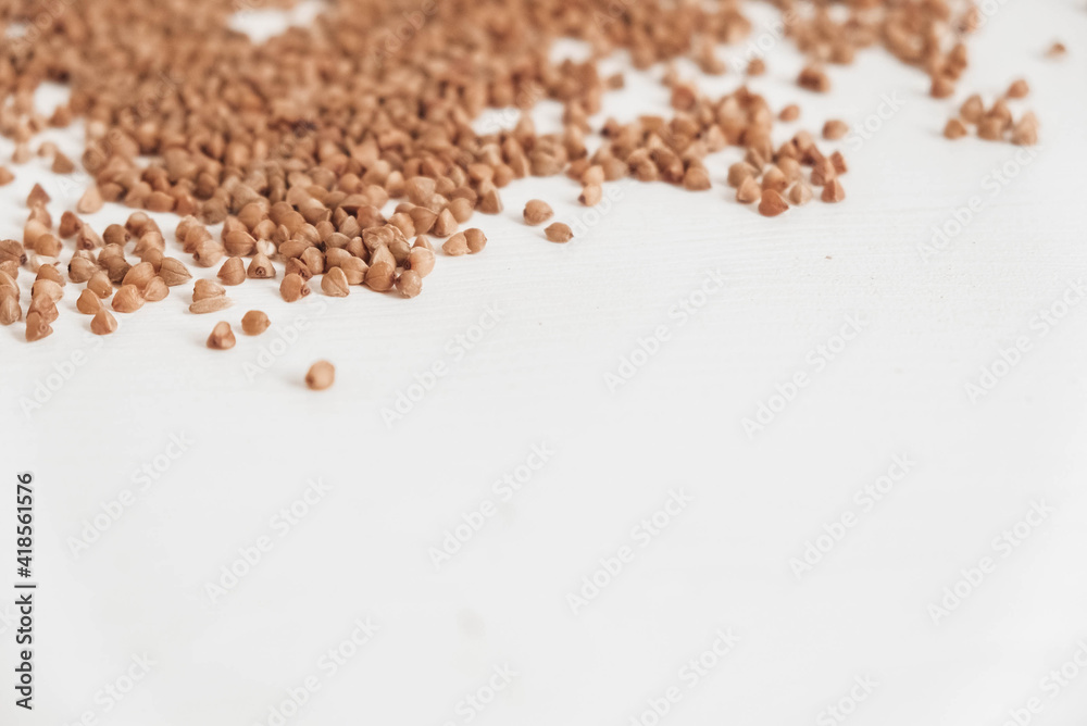 Buckwheat is randomly scattered on a white background. Top view. Copy, empty space for text Buckwheat is randomly scattered on a white background. Top view. Copy, empty space for text