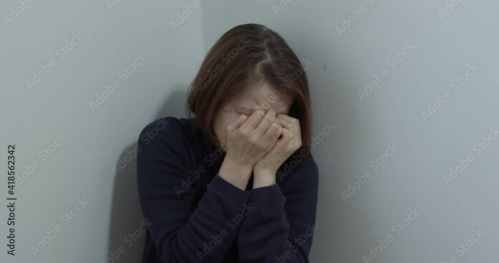 The concept of violence against a woman, in the family. A frightened girl sits in the corner of the room.
