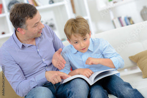 Father with young son holding book but distracted