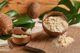 Bowl with coconut flour and scoop on wooden background
