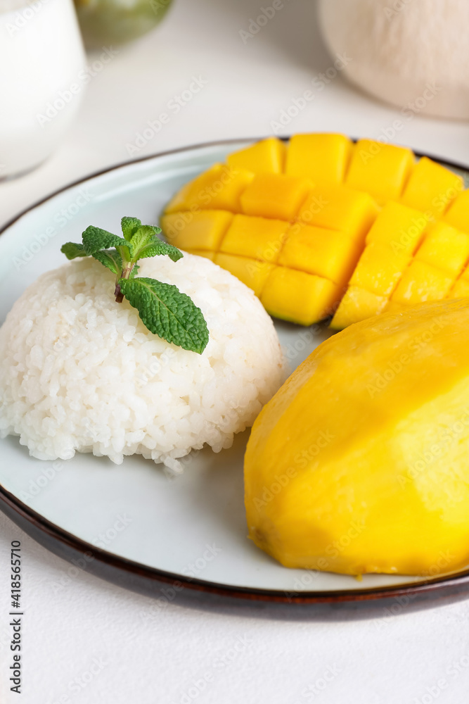 Plate with tasty rice and mango on light wooden background, closeup