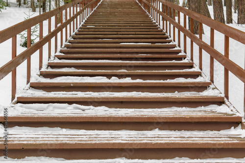 Wooden stairs up. White snow in winter. Handrails on the gum.