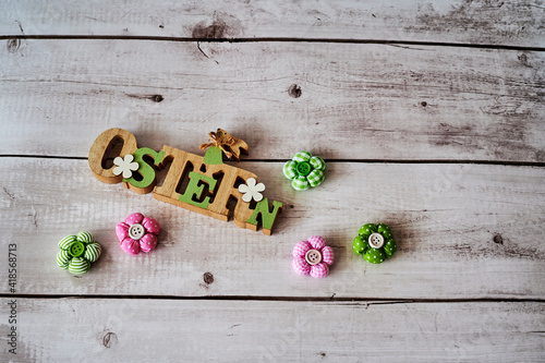 Wooden sign with an Easter bunny with flowers as decoration. The Text is German for Easter.