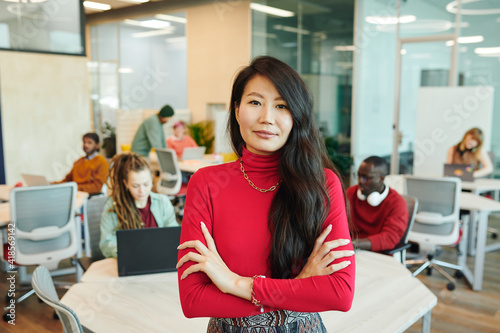 Young smiling businesswoman of Asian ethnicity crossing her arms by chest