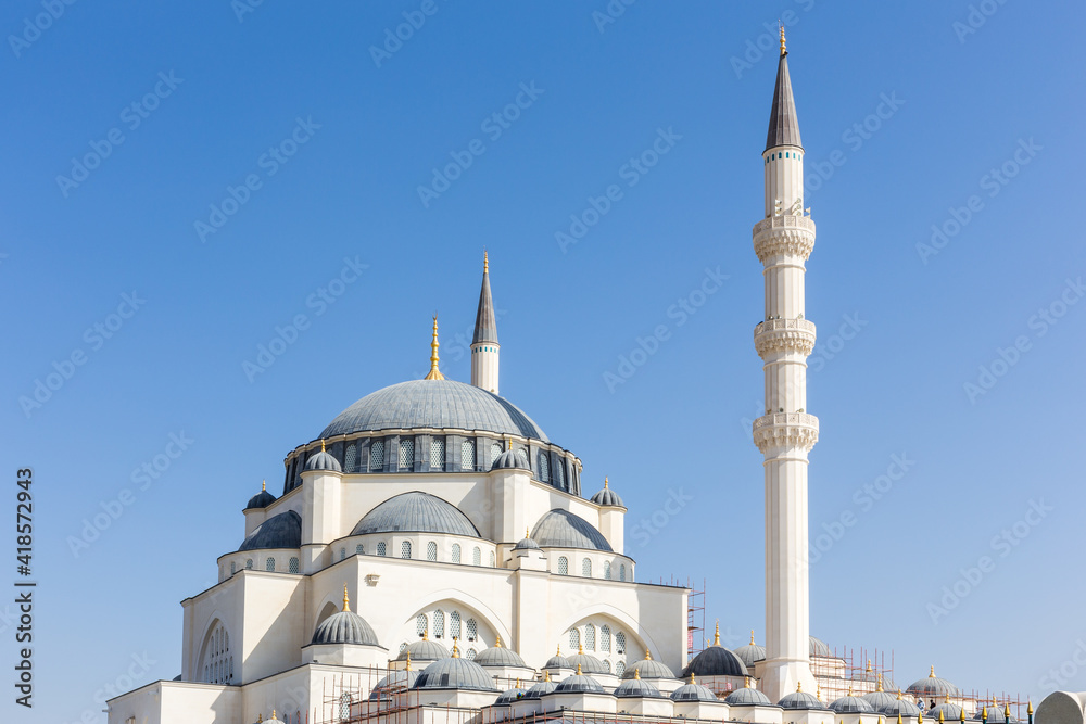 Fototapeta premium Dome and minaret of Sharjah Masjid mosque, The New Sharjah Mosque, the largest mosque in the Emirate of Sharjah, the United Arab Emirates, white sandstone facade with arched windows.