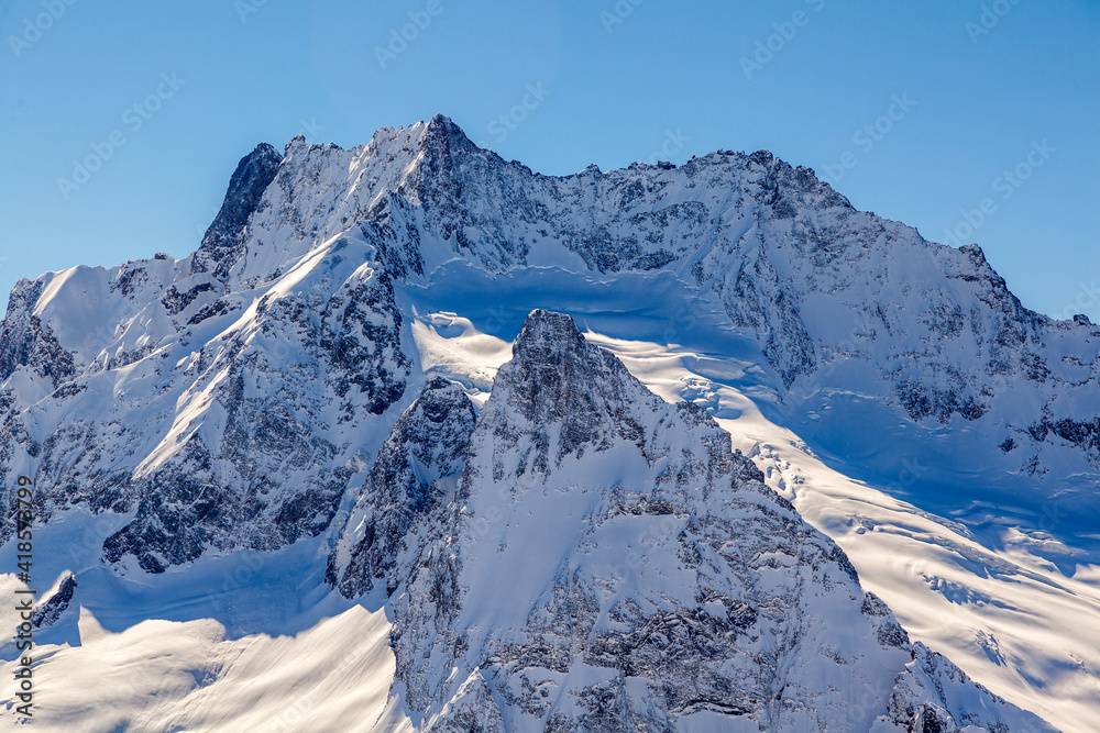 Caucasus Mountains, Panoramic view of the ski slope with the mountains Belalakaya, Sofrudzhu and Sulakhat on the horizon in winter day. Dombai ski resort, Western Caucasus, Karachai-Cherkess, Russia. Caucasus Mountains, Panoramic view of the ski slope with the mountains Belalakaya, Sofrudzhu and Sulakhat on the horizon in winter day. Dombai ski resort, Western Caucasus, Karachai-Cherkess, Russia.