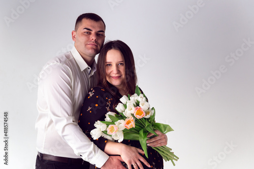 The guy hugs the pregnant girl's belly. Love and relationships on white background. Husband and pregnant wife on a white background.