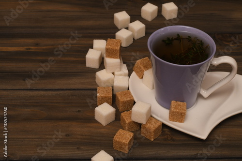 a mug of herbal tea on a wooden table with pieces of cane sugar