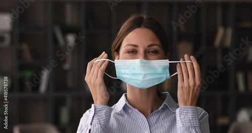 Caucasian happy 35s woman looking at camera, taking off protective disposable facemask, feeling relieved breathing fresh air indoors, personal safety quarantine covd19 measures, pandemic outbreak. photo