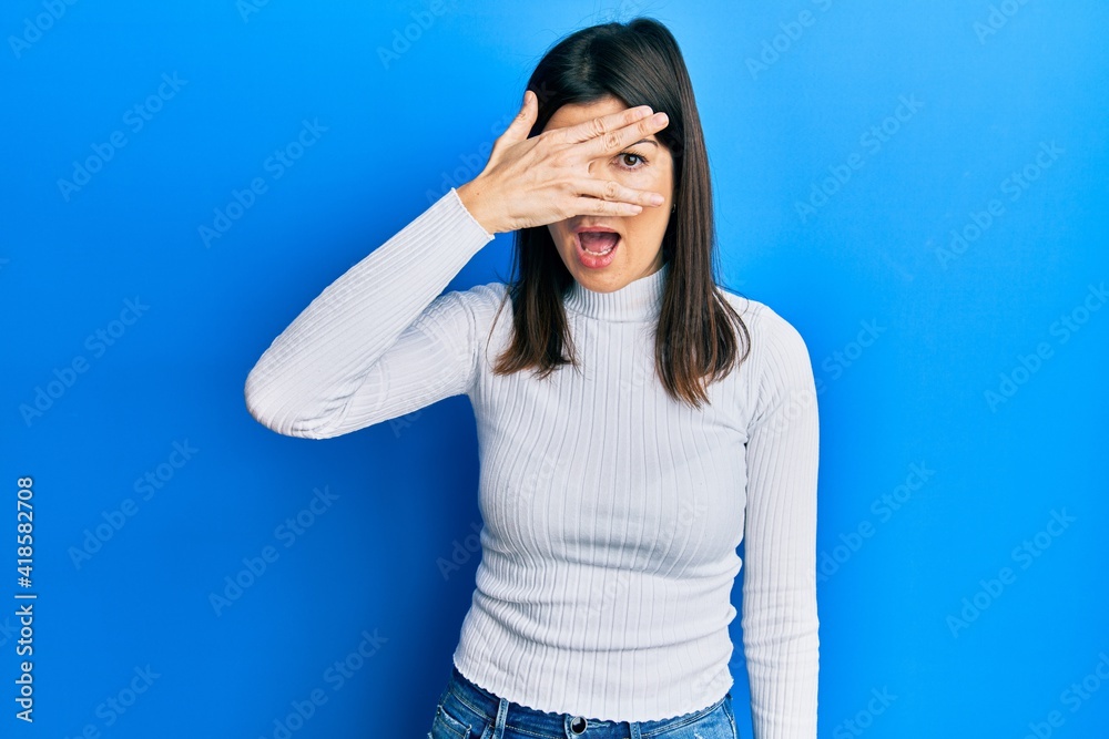 Young hispanic woman wearing casual clothes peeking in shock covering face and eyes with hand, looking through fingers afraid Young hispanic woman wearing casual clothes peeking in shock covering face and eyes with hand, looking through fingers afraid