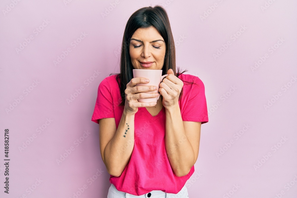 Young hispanic woman drinking a cup of coffee thinking attitude and sober expression looking self confident Young hispanic woman drinking a cup of coffee thinking attitude and sober expression looking self confident
