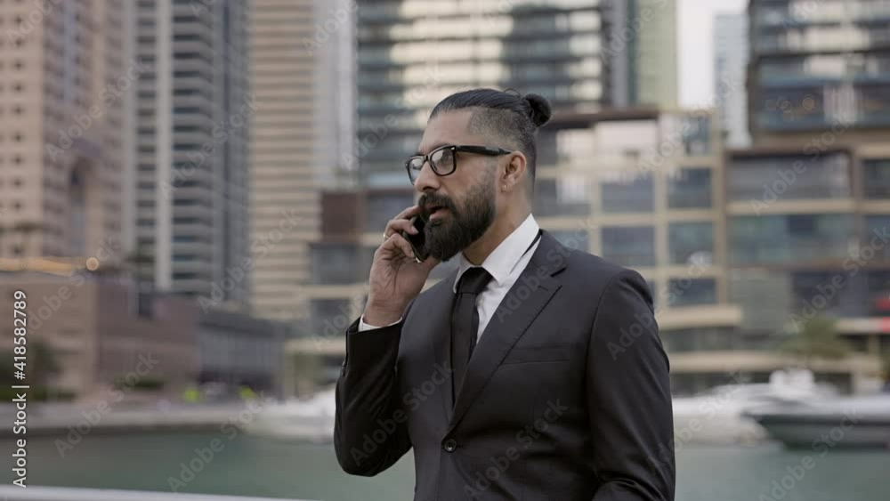 Stylish Young Man In Business Suit On Background Of The City. Tall Buildings Dubai. He Is Talking On The Phone. Stylish Young Man In Business Suit On Background Of The City. Tall Buildings Dubai. He Is Talking On The Phone.