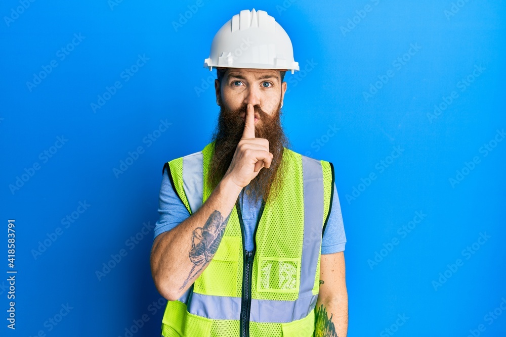 Redhead man with long beard wearing safety helmet and reflective jacket asking to be quiet with finger on lips. silence and secret concept. Redhead man with long beard wearing safety helmet and reflective jacket asking to be quiet with finger on lips. silence and secret concept.