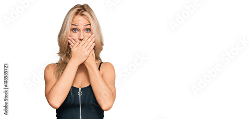 Young blonde girl wearing elegant and sexy look shocked covering mouth with hands for mistake. secret concept.
