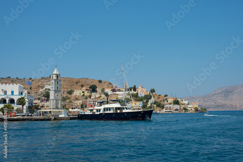 View of colorful Symi island with a big black ship. Symi, Dodecanese, Greece © Majopez