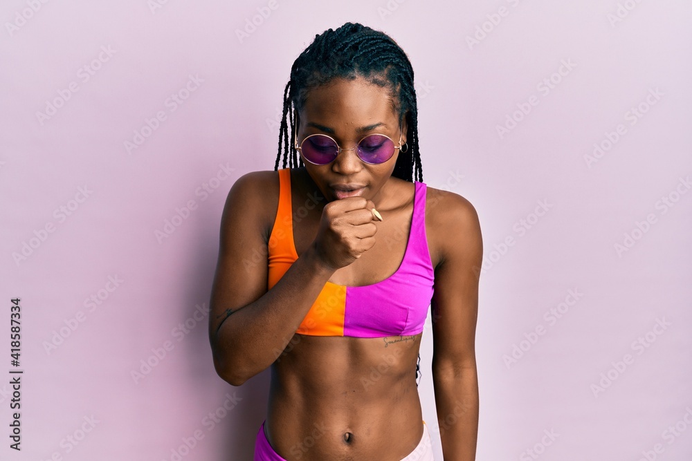 Young african american woman wearing bikini and sunglasses feeling unwell and coughing as symptom for cold or bronchitis. health care concept.