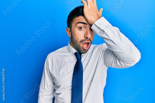 Young hispanic man wearing business clothes surprised with hand on head for mistake, remember error. forgot, bad memory concept.